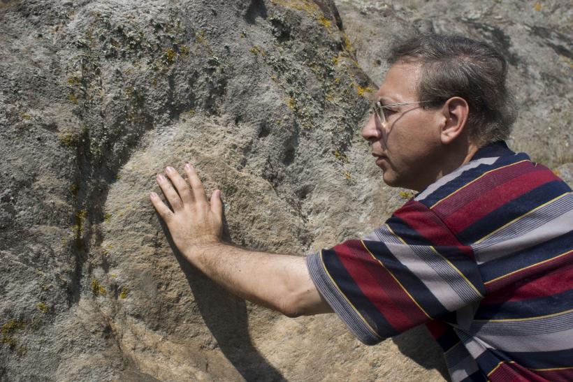 Д-р Васил Добрев разглежда едно от стотиците издялани в скалите на Палеокастро слънца.
